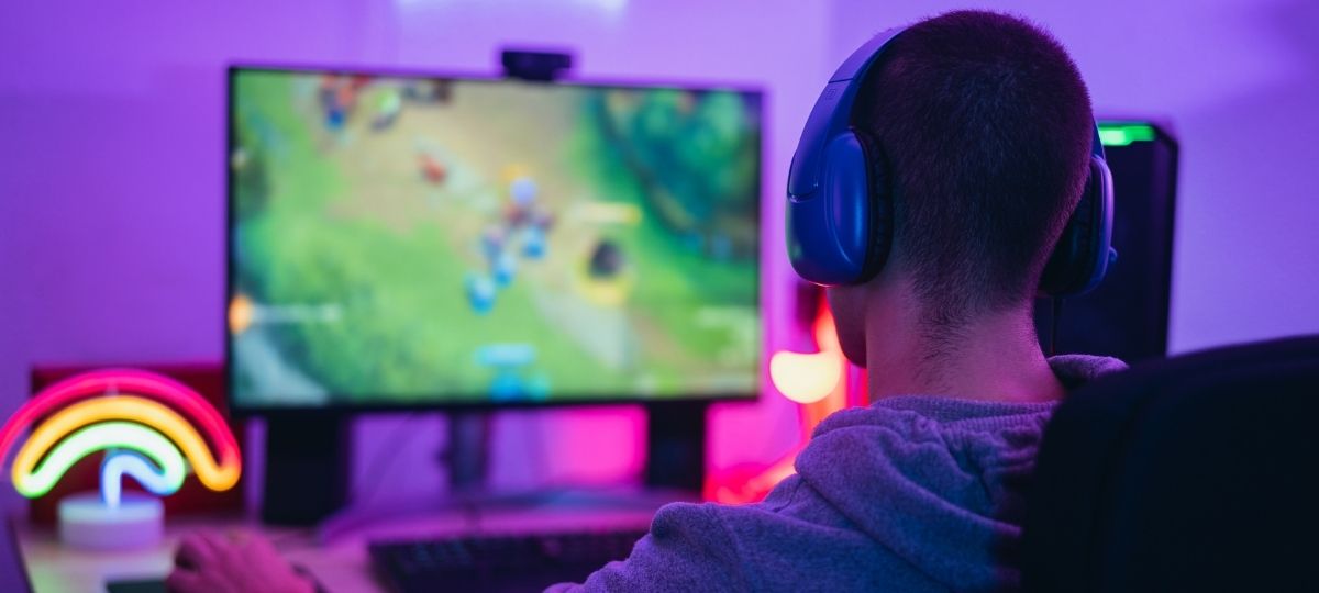 A photo of a young man playing video games at his desk from behind