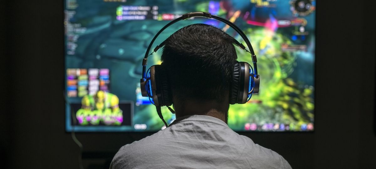 young dude playing video games on his computer in a darkroom