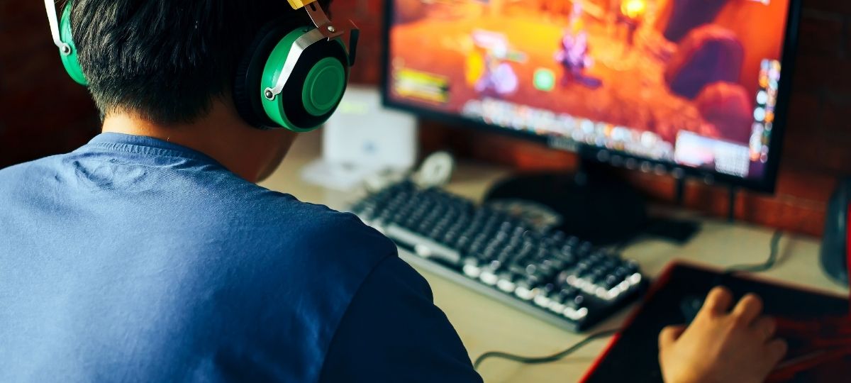 A boy extremely focused on his video games while in his dark bedroom.