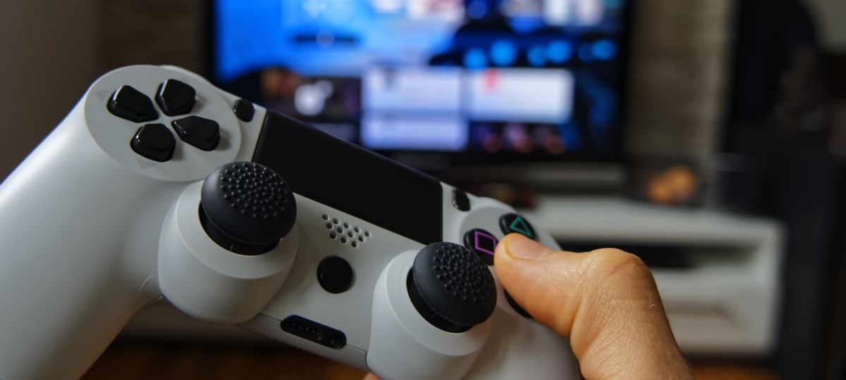 Point of view photo of someone holding a PS3 controller with a monitor in the distance