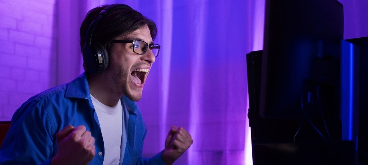 A young man looking excited while in his room playing video games