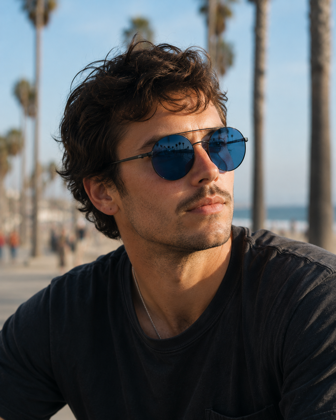 Man wearing sunglasses with palm trees and a beach in the background #Color_Matte Black/Blue Lens