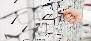 An optometrist selecting a pair of glasses off a display wall in an office