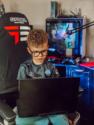 A boy using gaming glasses while using a laptop in his bedroom