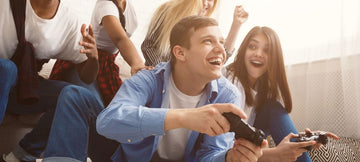 A man playing video games with a group of friends while a female looks very intrigued