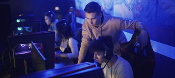 A young man looking over his teammates gameplay while at a gaming competition