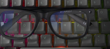 Pair of gaming glasses laying on a LED lit keyboard