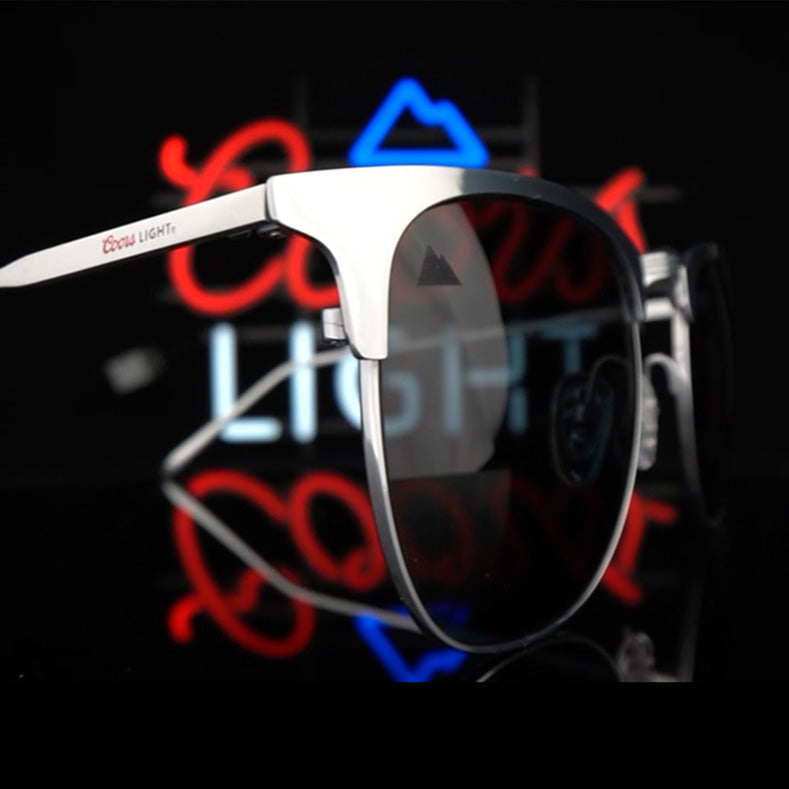 Coors Light sunglasses product shot with a neon coors light logo in the background
