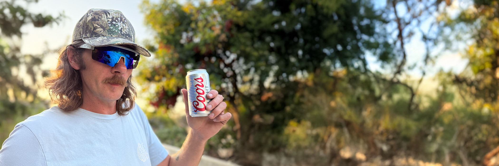 Person holding a can outdoors with trees in the background