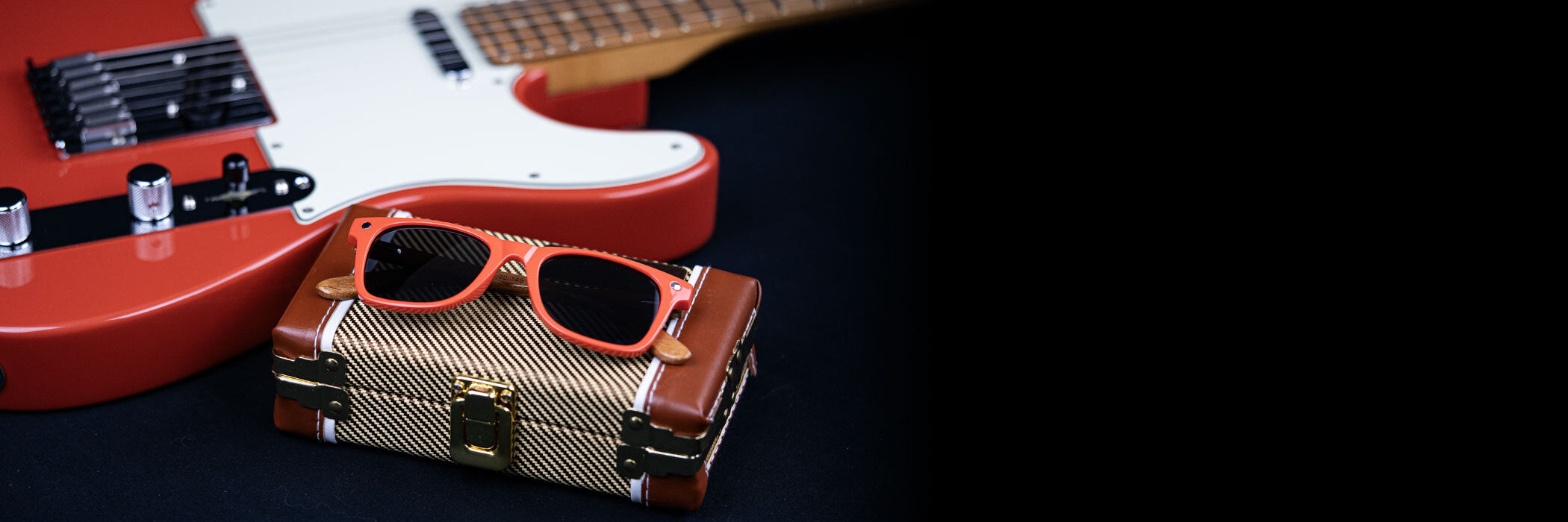 Fender sunglasses on a fender case next to a guitar