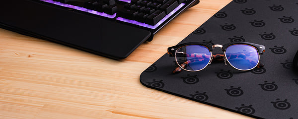 Gaming glasses sitting on a mousepad gaming set up