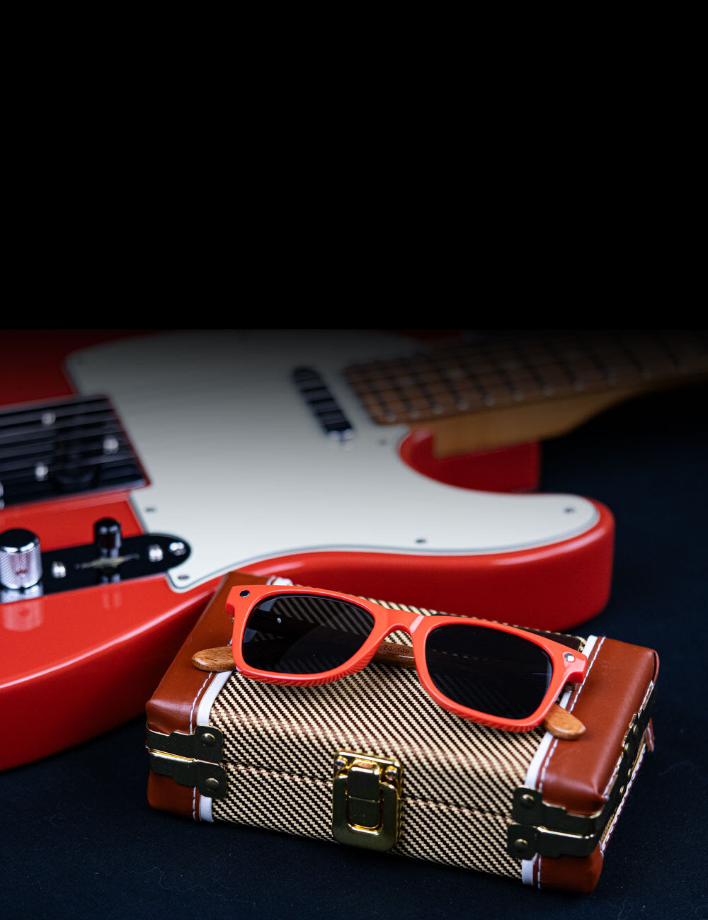 Fender sunglasses on a fender case next to a guitar