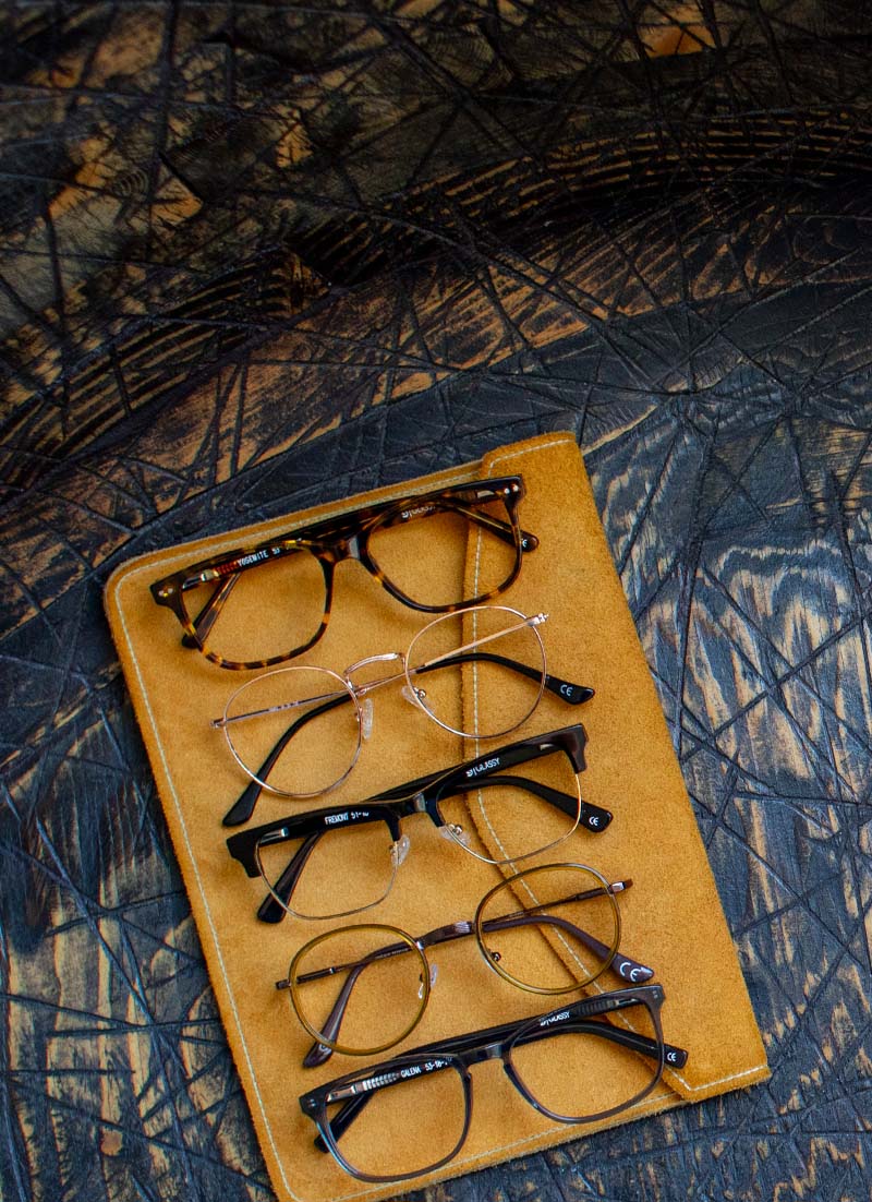 5 pairs of prescription glasses sitting on a notebook on a table
